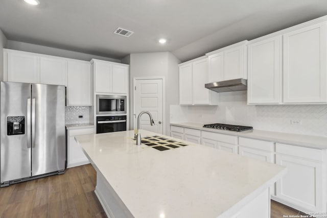kitchen with stainless steel appliances, a sink, under cabinet range hood, recessed lighting, and tasteful backsplash
