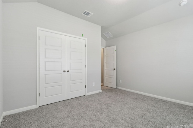 unfurnished bedroom with carpet floors, a closet, baseboards, and lofted ceiling