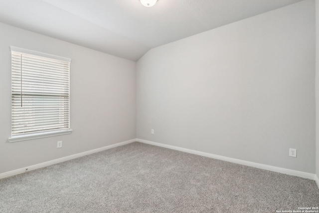 carpeted empty room with lofted ceiling and baseboards