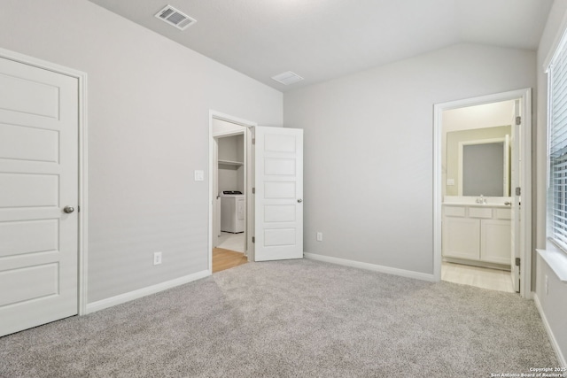 unfurnished bedroom with carpet floors, baseboards, vaulted ceiling, and washer / dryer