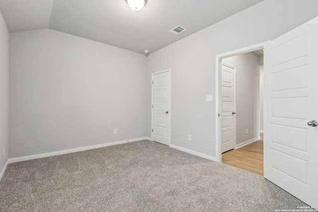 unfurnished bedroom featuring carpet flooring, lofted ceiling, and baseboards