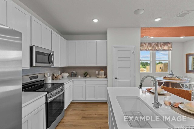 6879 Comanche Cave, San Antonio, TX 78247 - kitchen featuring sink, stainless steel appliances, light hardwood / wood-style floors, and white cabinets