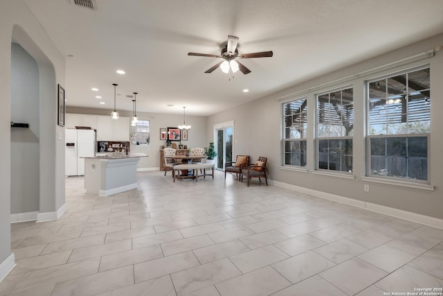 living room featuring light tile patterned flooring and ceiling fan with notable chandelier