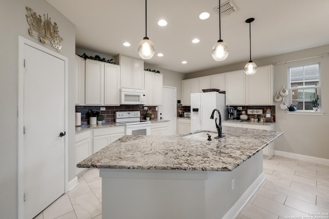 kitchen with white appliances, an island with sink, hanging light fixtures, and white cabinets