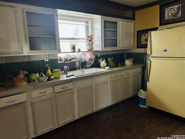 kitchen with tasteful backsplash, tile counters, refrigerator, and sink