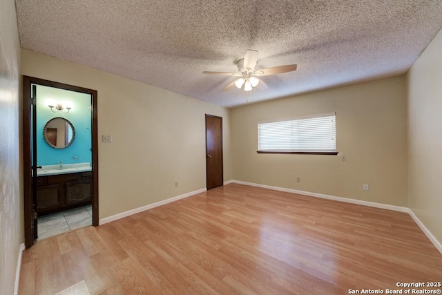 spare room featuring light wood-type flooring, ceiling fan, and a textured ceiling