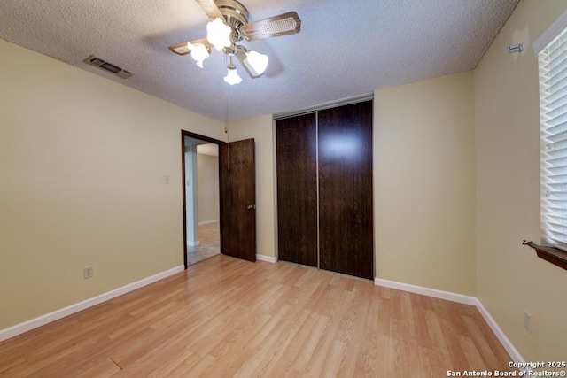 unfurnished bedroom featuring light hardwood / wood-style floors, a closet, ceiling fan, and a textured ceiling