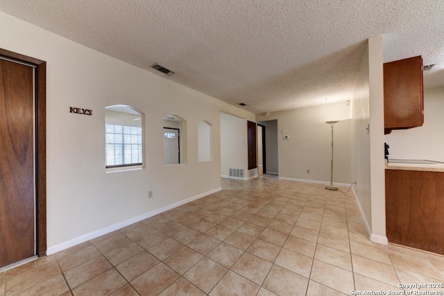 empty room featuring a textured ceiling and light tile patterned flooring