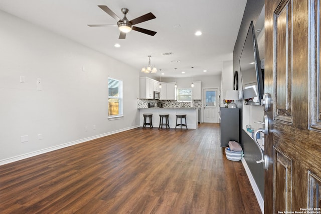 living room with dark hardwood / wood-style flooring and ceiling fan with notable chandelier