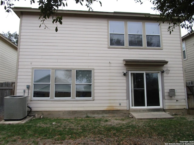 rear view of house with central AC and a yard