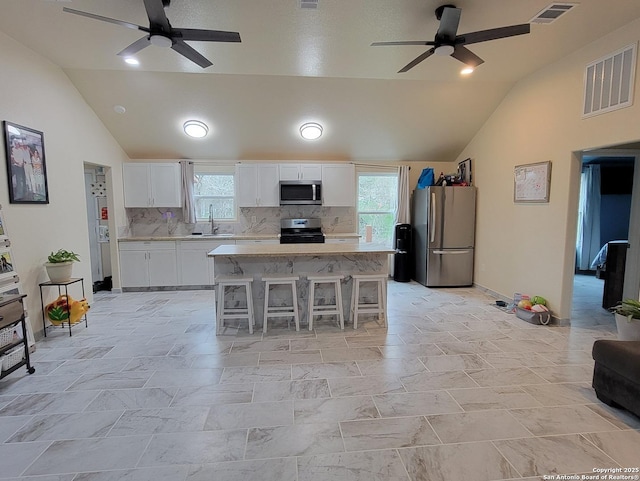 kitchen with sink, white cabinets, a kitchen breakfast bar, a center island, and stainless steel appliances