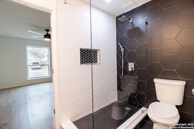 bathroom with ceiling fan, tile walls, a tile shower, wood-type flooring, and toilet