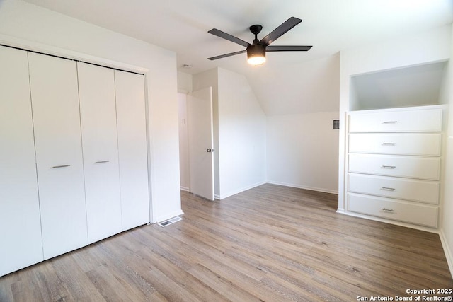 unfurnished bedroom featuring a closet, lofted ceiling, ceiling fan, and light hardwood / wood-style flooring