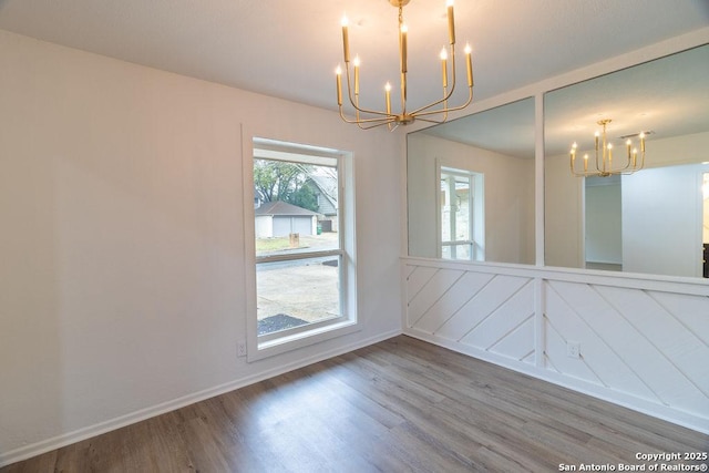 unfurnished dining area with hardwood / wood-style floors and a notable chandelier