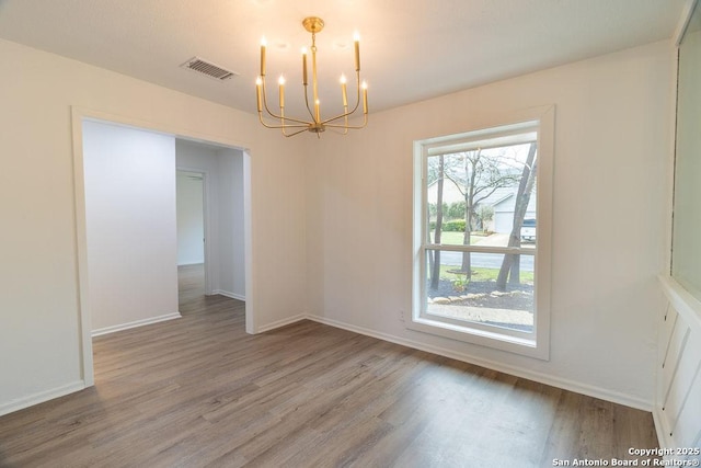 empty room featuring a notable chandelier and hardwood / wood-style flooring