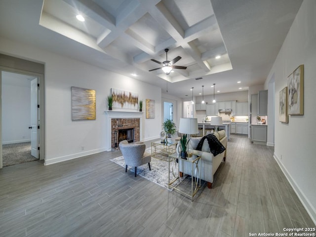 living room featuring hardwood / wood-style flooring, coffered ceiling, a fireplace, and beam ceiling