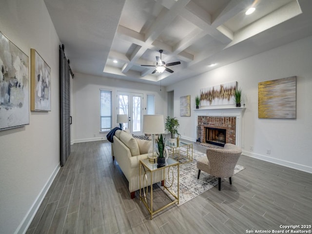 living room featuring a fireplace, coffered ceiling, ceiling fan, a barn door, and beam ceiling