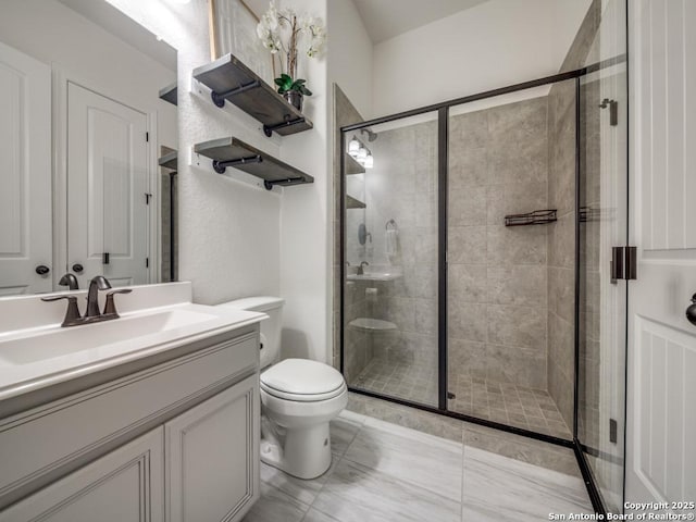 bathroom featuring vanity, a shower with door, and toilet