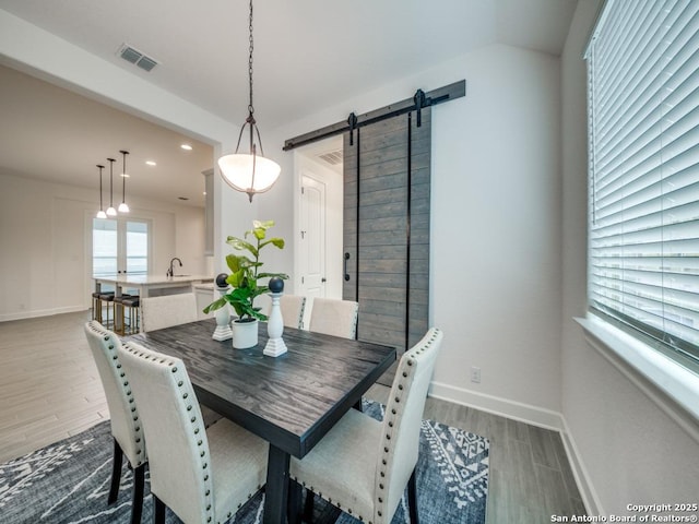 dining area featuring a barn door, sink, and hardwood / wood-style floors