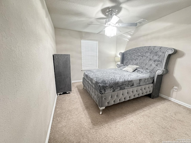 bedroom with ceiling fan, light carpet, and a textured ceiling