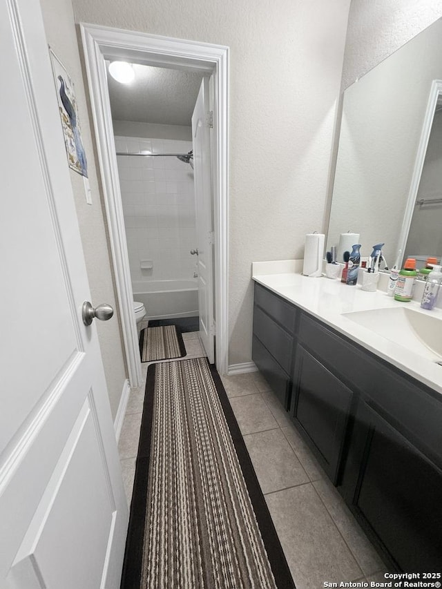 full bathroom featuring tile patterned floors, toilet, a textured ceiling, vanity, and tiled shower / bath combo