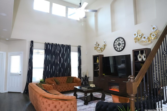 living room with dark hardwood / wood-style floors, ceiling fan, and a high ceiling