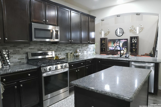 kitchen featuring stainless steel appliances, a center island, sink, and decorative backsplash