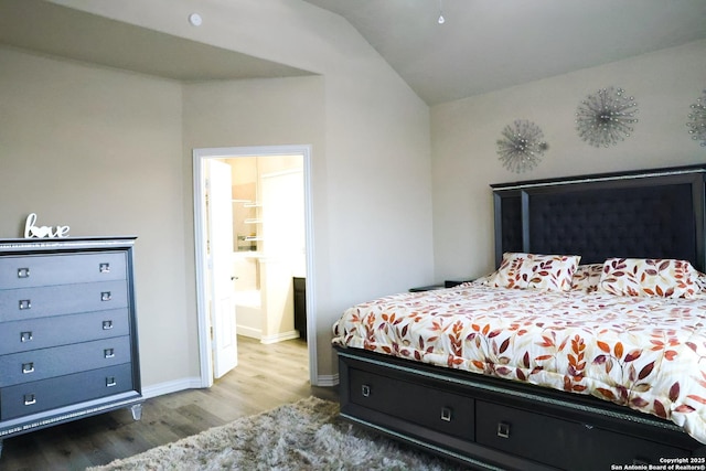 bedroom with lofted ceiling, ensuite bath, and wood-type flooring