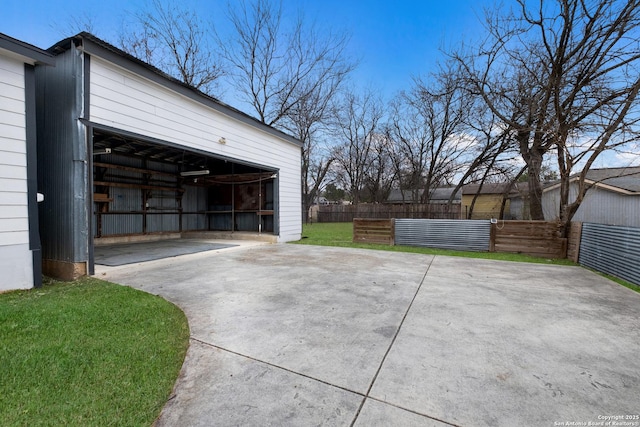 garage featuring concrete driveway and fence