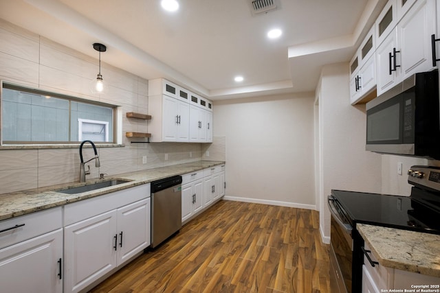 kitchen with hanging light fixtures, glass insert cabinets, appliances with stainless steel finishes, white cabinetry, and a sink