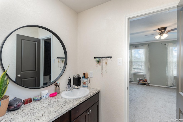 bathroom featuring ceiling fan, ornamental molding, and vanity