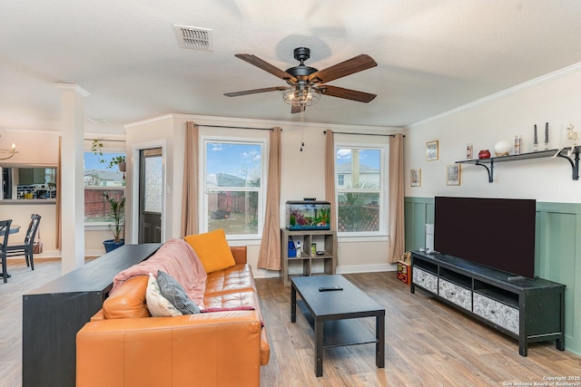 living room with crown molding, ceiling fan with notable chandelier, light hardwood / wood-style floors, and a textured ceiling