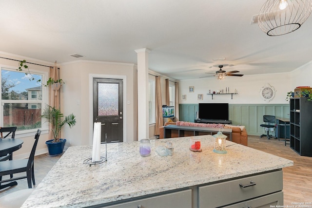 kitchen with a center island, ceiling fan, crown molding, light stone countertops, and light hardwood / wood-style flooring