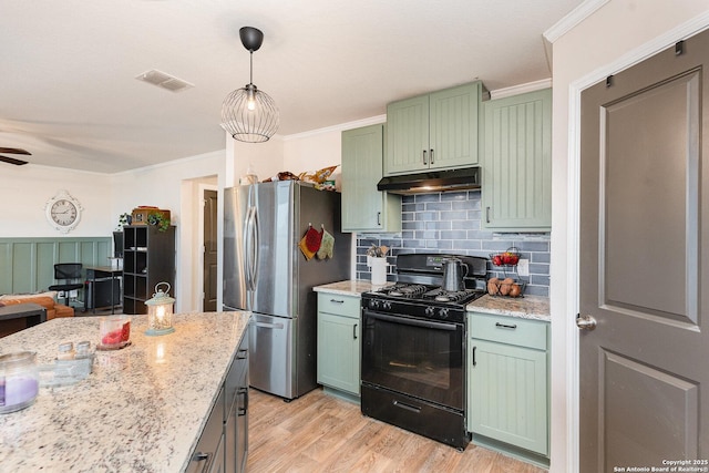 kitchen featuring black gas range oven, pendant lighting, stainless steel refrigerator, green cabinets, and light stone countertops