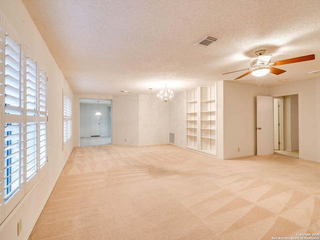 carpeted spare room featuring ceiling fan with notable chandelier, built in features, and a textured ceiling