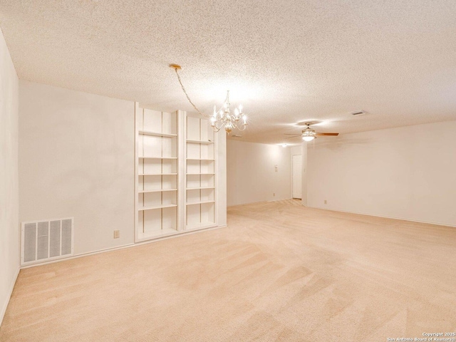 carpeted empty room with ceiling fan with notable chandelier and a textured ceiling