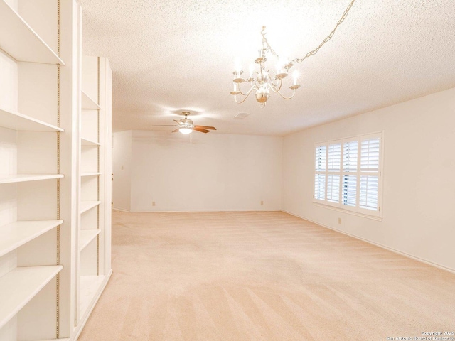 spare room with ceiling fan with notable chandelier, light colored carpet, and a textured ceiling