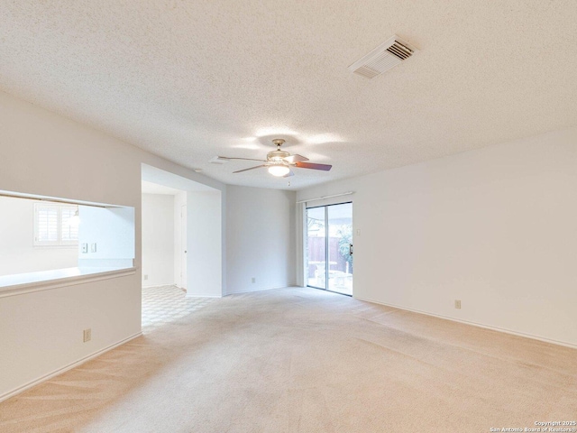 spare room featuring ceiling fan, light carpet, and a textured ceiling