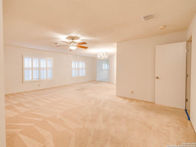 carpeted empty room with ceiling fan with notable chandelier and a textured ceiling