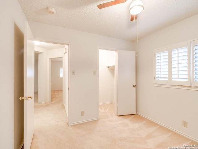 unfurnished bedroom with a spacious closet, light colored carpet, and a textured ceiling