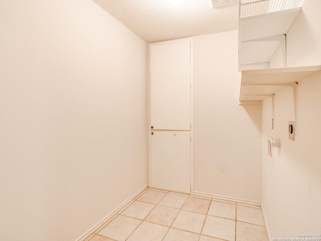 laundry room featuring a textured ceiling and light tile patterned floors