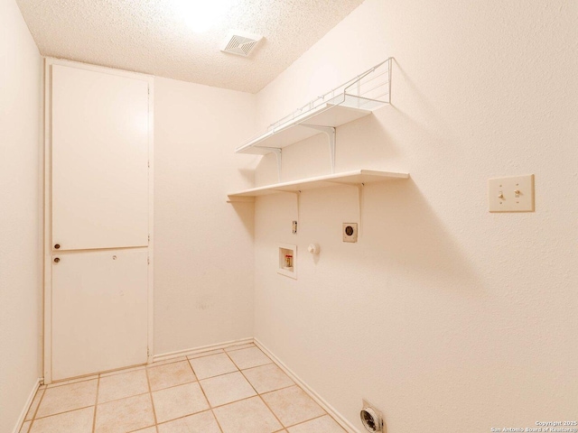 washroom featuring gas dryer hookup, a textured ceiling, light tile patterned floors, electric dryer hookup, and washer hookup