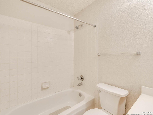 bathroom with toilet, tiled shower / bath combo, and a textured ceiling