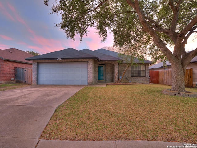 ranch-style home with a garage and a yard