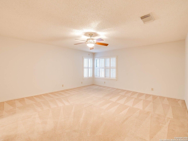 spare room featuring ceiling fan, light carpet, and a textured ceiling