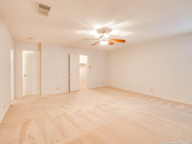 empty room featuring light carpet, a textured ceiling, and ceiling fan