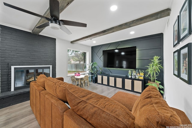 living room with a brick fireplace, beamed ceiling, and light wood-type flooring