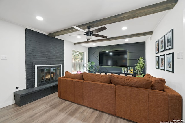 living room with beamed ceiling, ceiling fan, a fireplace, and light hardwood / wood-style flooring