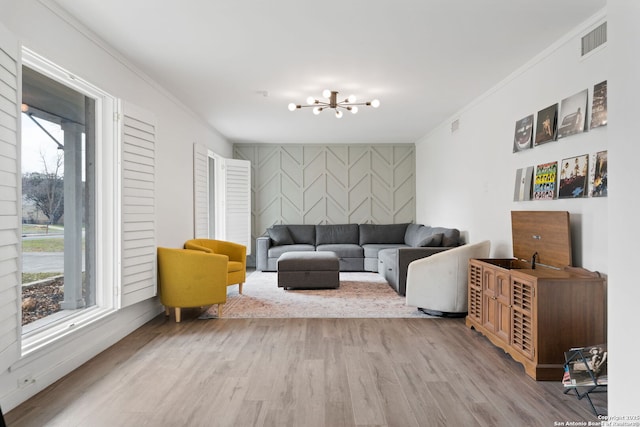 living room with wood-type flooring, ornamental molding, and a chandelier