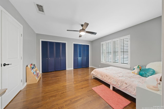 bedroom featuring multiple closets, ceiling fan, and hardwood / wood-style floors